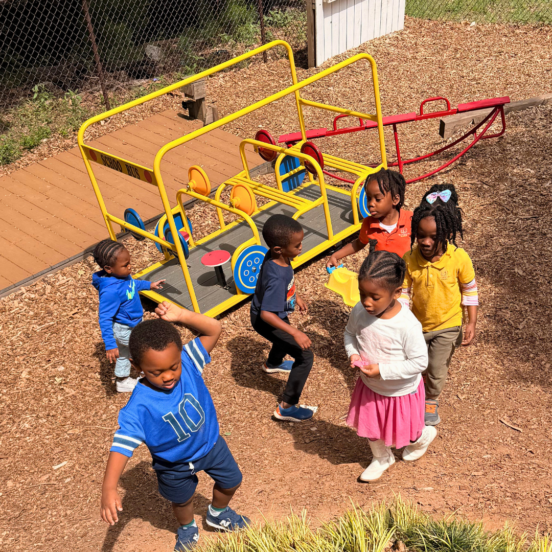 Scholars playing together outside on our school-bus playground structure