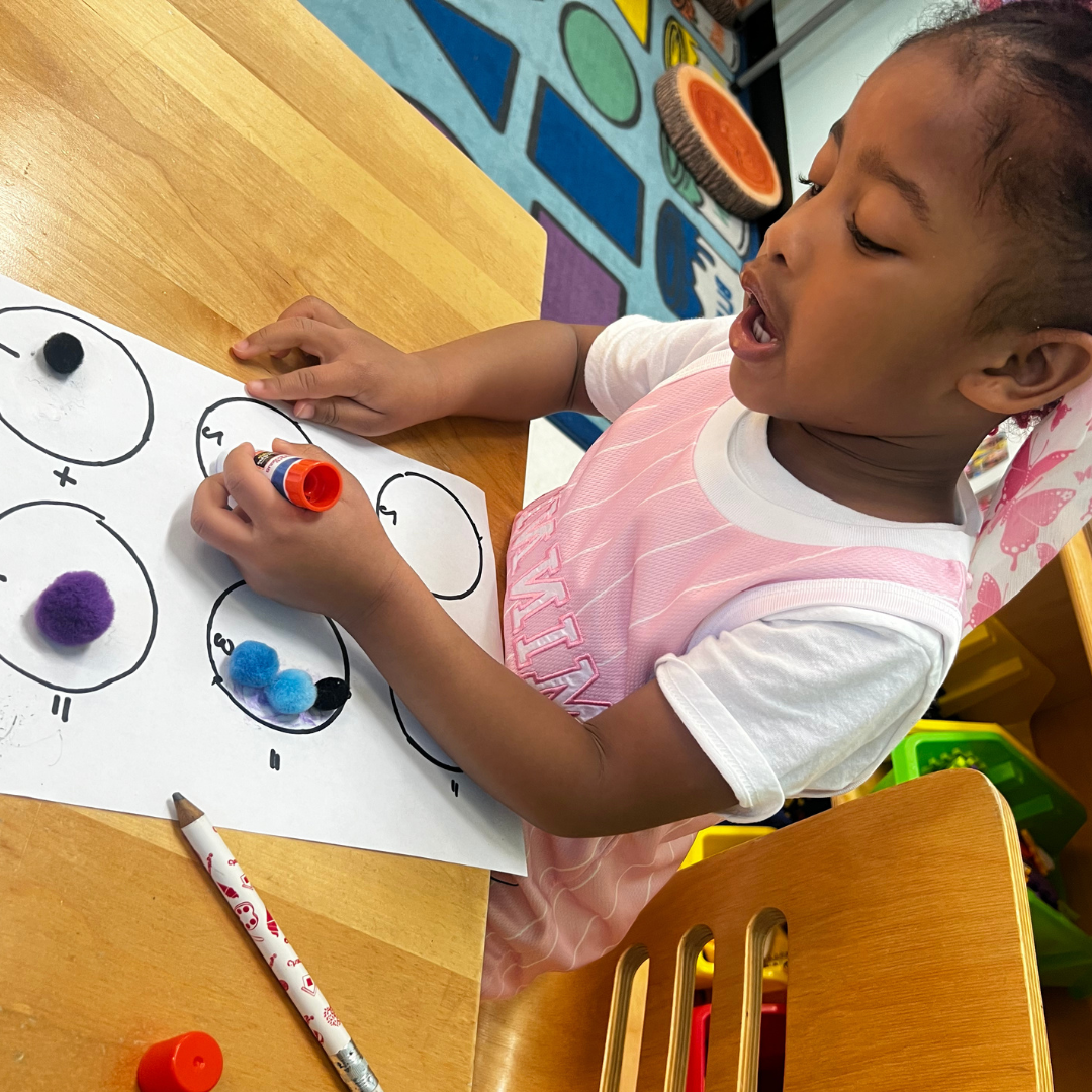 A young scholar focused on a hands-on counting activity with pom-poms