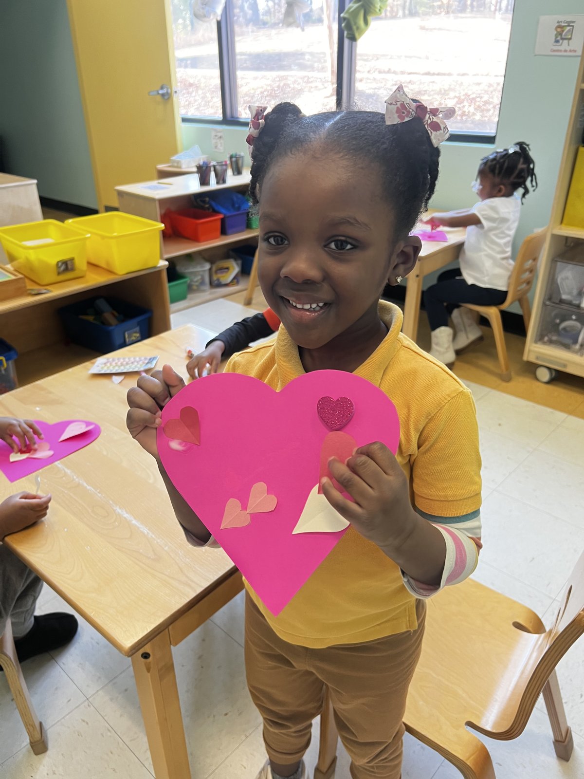 Smiling scholar holding a handmade paper heart at The Astounding Academy