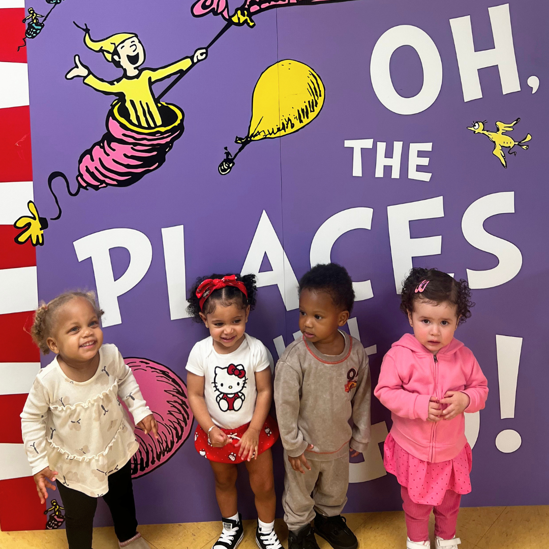 Young scholars in front of a colorful Dr. Seuss reading mural