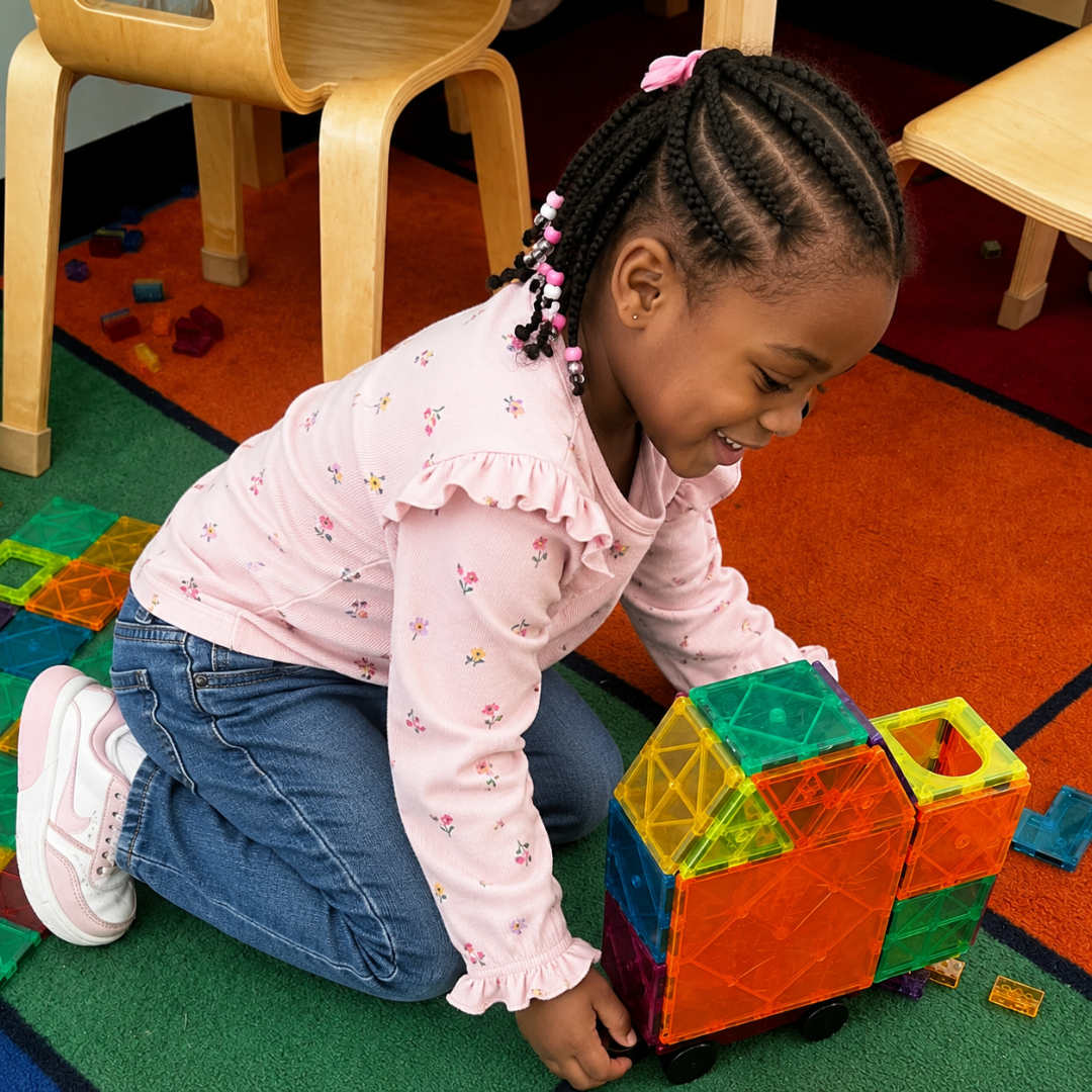 Pre-K scholar building creatively with colorful magnetic tiles