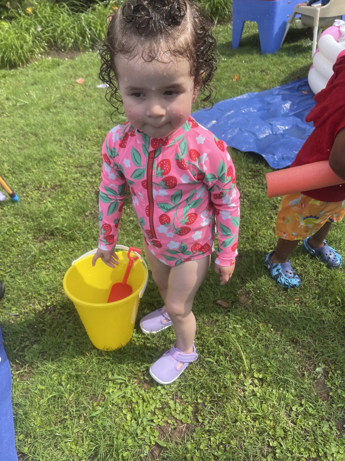Toddler exploring outdoor water play with a bucket